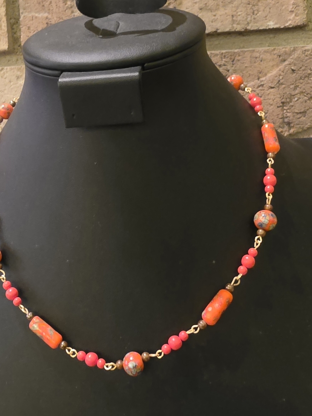 Vintage beaded necklace features bright orange cylindrical and round glass beads